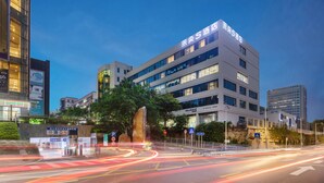 A modern hotel with multiple floors and a prominent sign. - Apex Hotel  (Shenzhen)