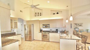 Una cocina amplia con encimeras de granito, electrodomésticos de acero inoxidable y una isla central.