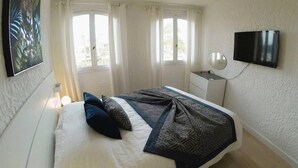 Une chambre à coucher avec un lit, une télévision et une fenêtre avec des rideaux.