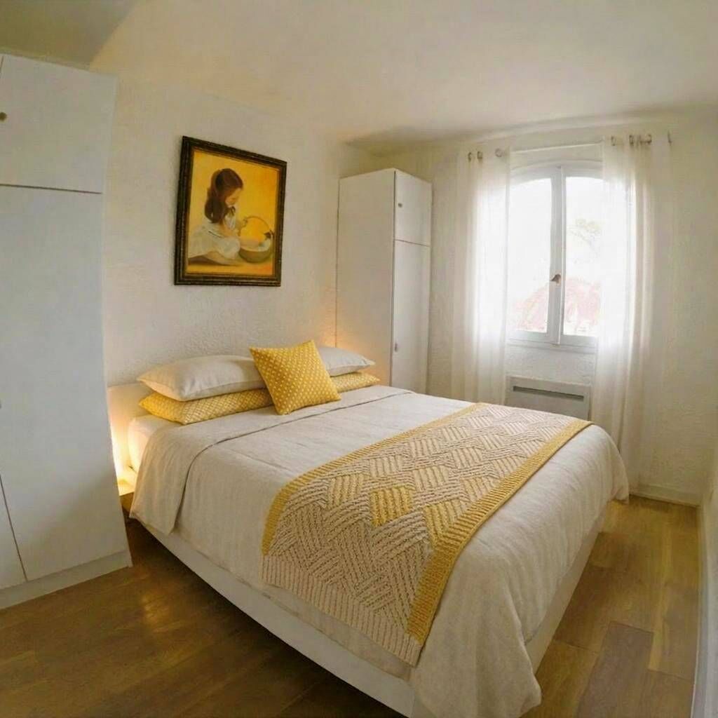 A bedroom with a bed, a wardrobe, a window with curtains, and a framed picture on the wall.