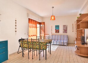 A compact living space with a dining table, a sofa, a TV, and a kitchen area.