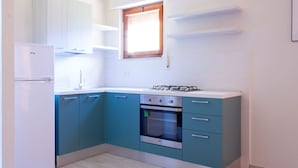 A modern kitchen with teal cabinets, a white refrigerator, a gas stove, and a window above the sink. - Vania, in Marina di Campo, is located in a residential area, convenient to the beach and services, w (Campo nell'Elba)
