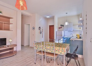 Un espace de vie compact comprenant un coin repas, une kitchenette et un téléviseur.