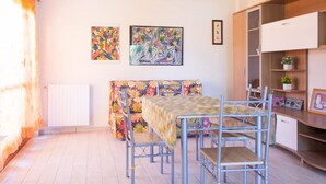 A dining area with a table, chairs, and artwork on the walls. - Vania, in Marina di Campo, is located in a residential area, convenient to the beach and services, w (Campo nell'Elba)