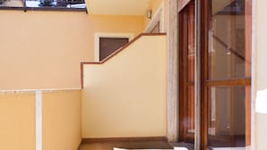A narrow corridor with a tiled floor, a wooden staircase, and a glass door leading to a room. - Vania, in Marina di Campo, is located in a residential area, convenient to the beach and services, w (Campo nell'Elba)