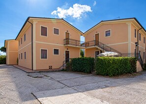 A two-story building with a flat roof, a balcony with a metal railing, and a staircase leading to the upper floor. - Vania, in Marina di Campo, is located in a residential area, convenient to the beach and services, w (Campo nell'Elba)
