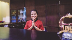 A reception area with a wooden counter, a statue, and a calendar displaying the date. - PIA Hotel Medan (Medan)
