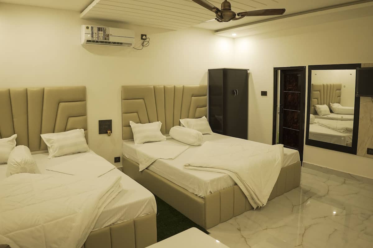 A hotel room with two beds, a ceiling fan, an air conditioning unit, a wardrobe, and a large mirror.