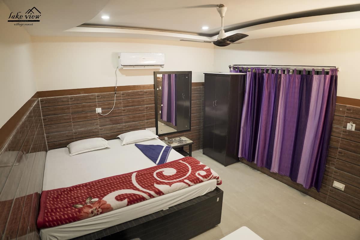 A hotel room with a bed, a wardrobe, a mirror, and a ceiling fan.