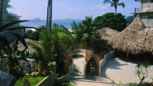 Un complexe hôtelier doté d’une structure à toit de chaume, de palmiers et offrant une vue sur la mer.