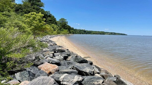 A rocky shoreline with a clear view of the water and a distant landmass.
