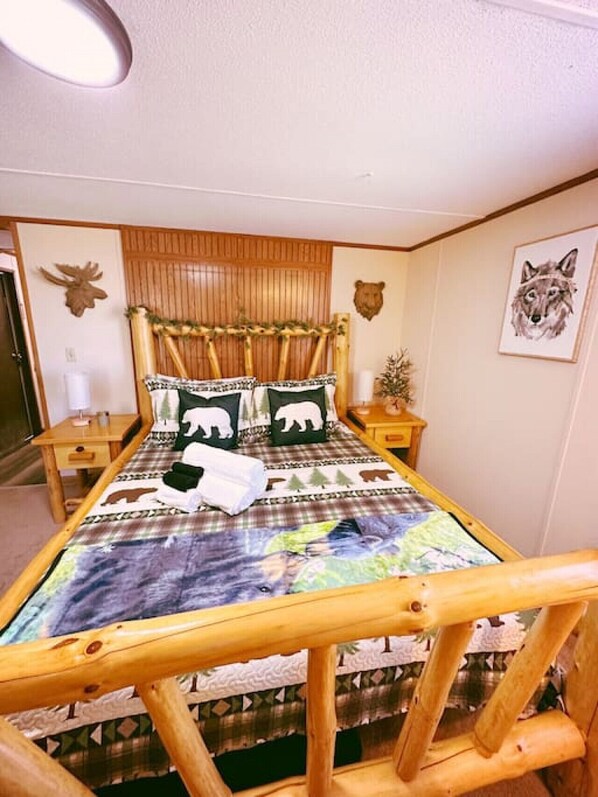Un lit en bois avec une tête de lit, deux tables de chevet et un mur décoré de motifs animaliers.