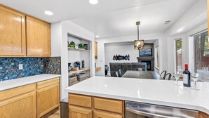 A modern kitchen with wooden cabinets, a white countertop, and a built-in dishwasher. - Under the Pines | Quiet Backyard & Neighborhood (Flagstaff)