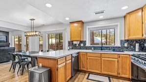 A modern kitchen with wooden cabinets, a large island, and a built-in stove. - Under the Pines | Quiet Backyard & Neighborhood (Flagstaff)