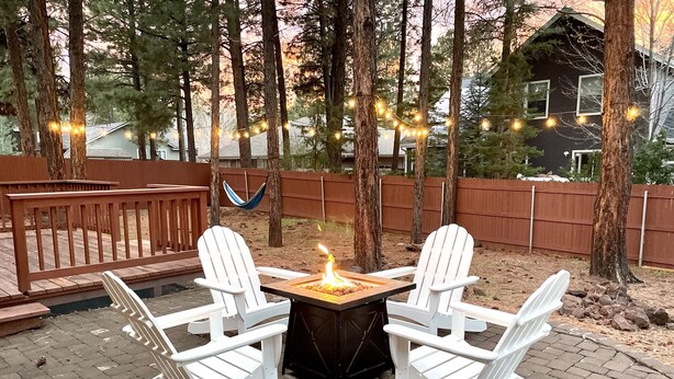 A patio with two white Adirondack chairs and a fire pit. - Under the Pines | Quiet Backyard & Neighborhood (Flagstaff)