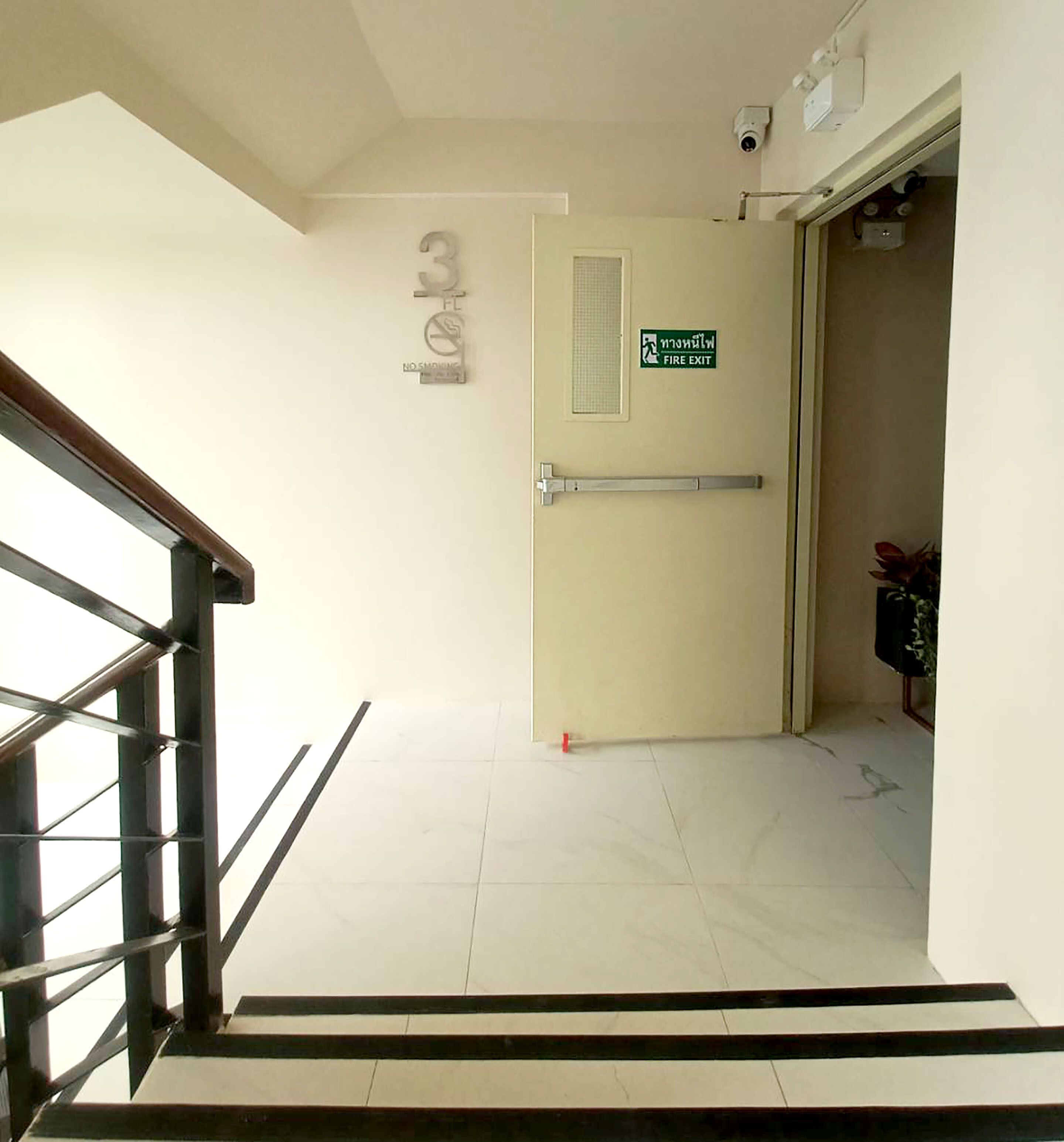 A stairway leading to a fire exit door with a sign indicating the exit.