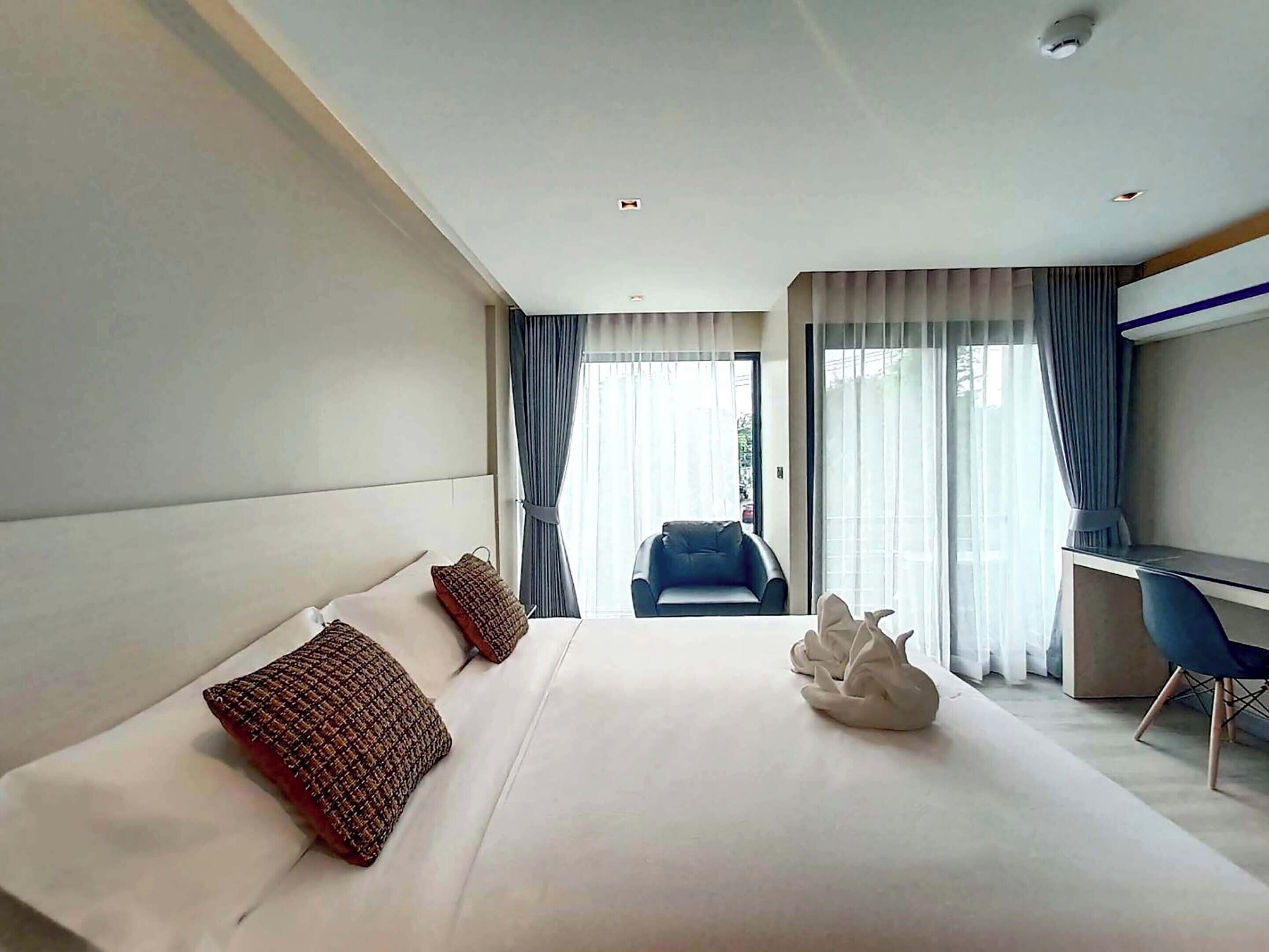 Una habitación de hotel moderna con una cama grande, un escritorio y una silla.
