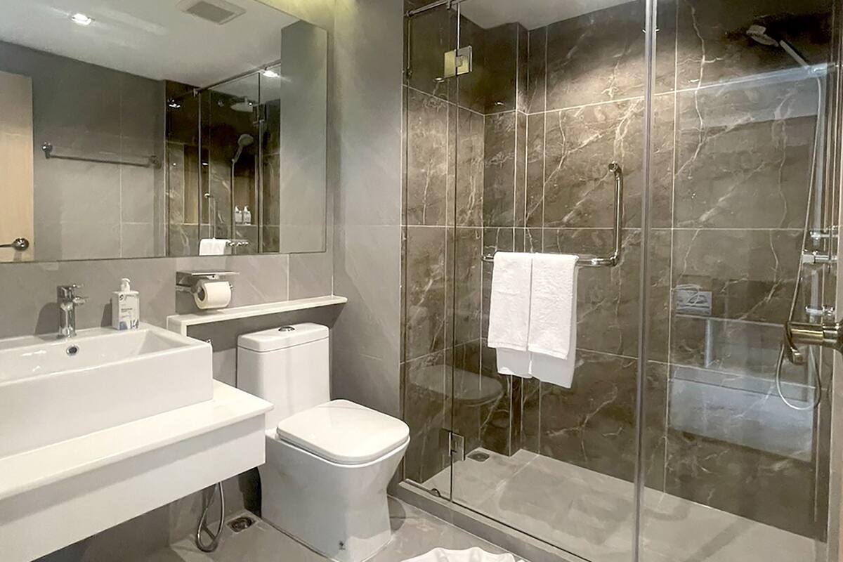 A modern bathroom with a glass-enclosed shower, a white sink, and a toilet.