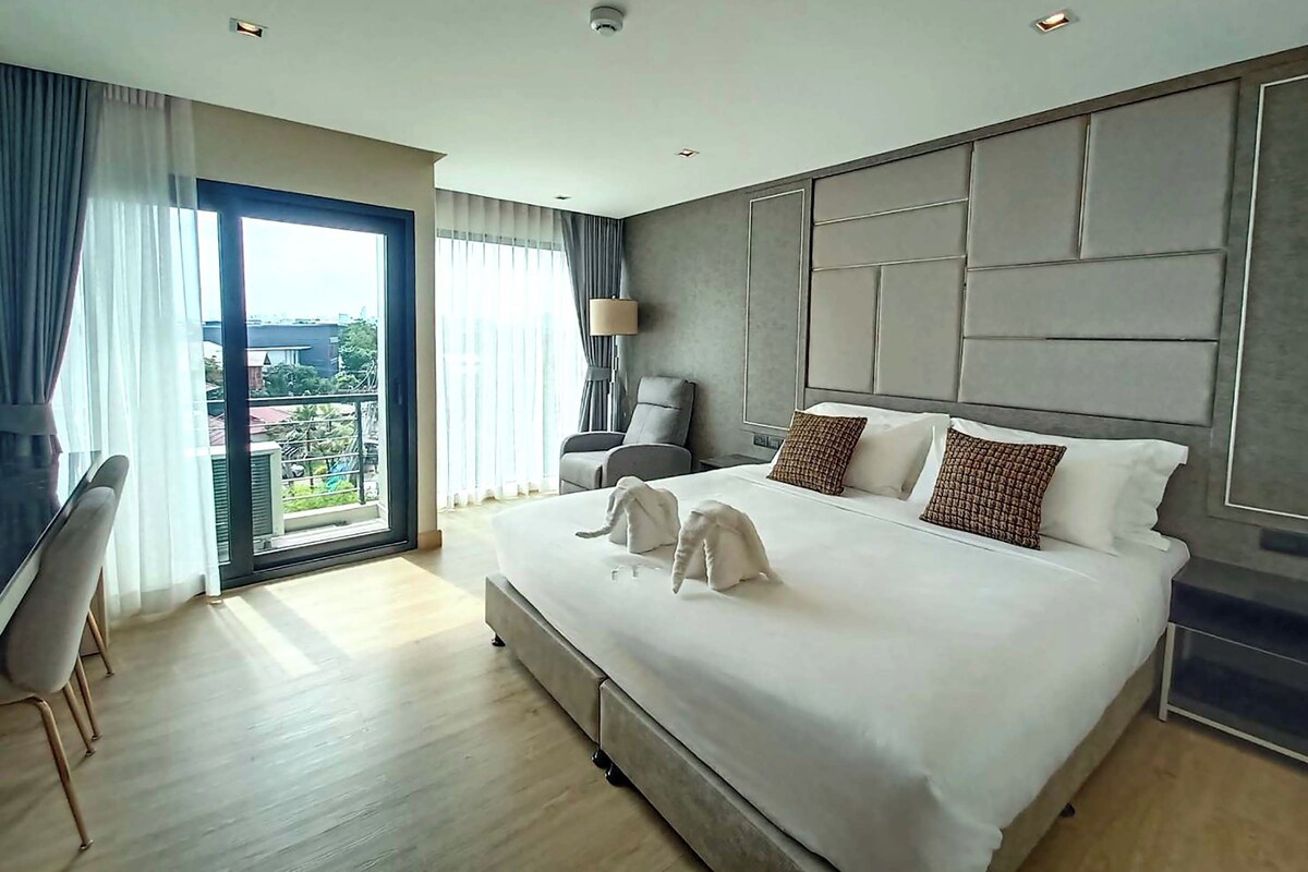 A hotel room with a large bed, a desk, and a view of the outdoors.