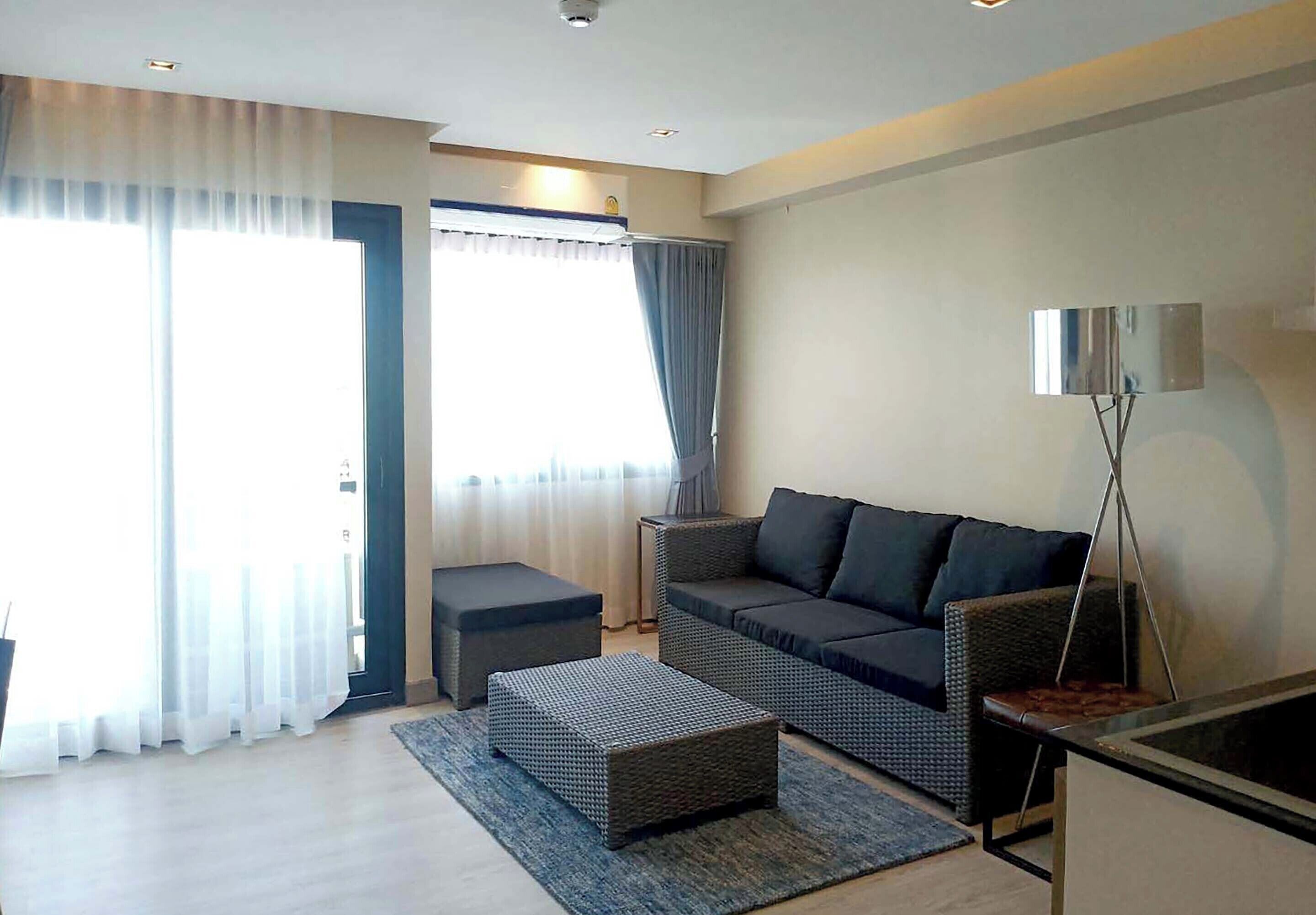 A modern living room with a sofa, ottoman, and a floor lamp.