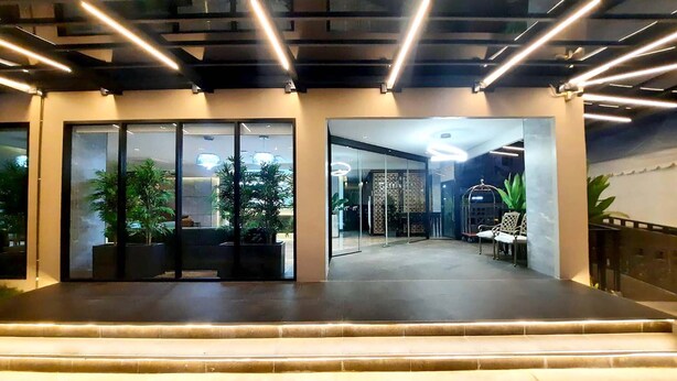 Um lobby moderno com portas de vidro, plantas em vasos e uma área de estar.