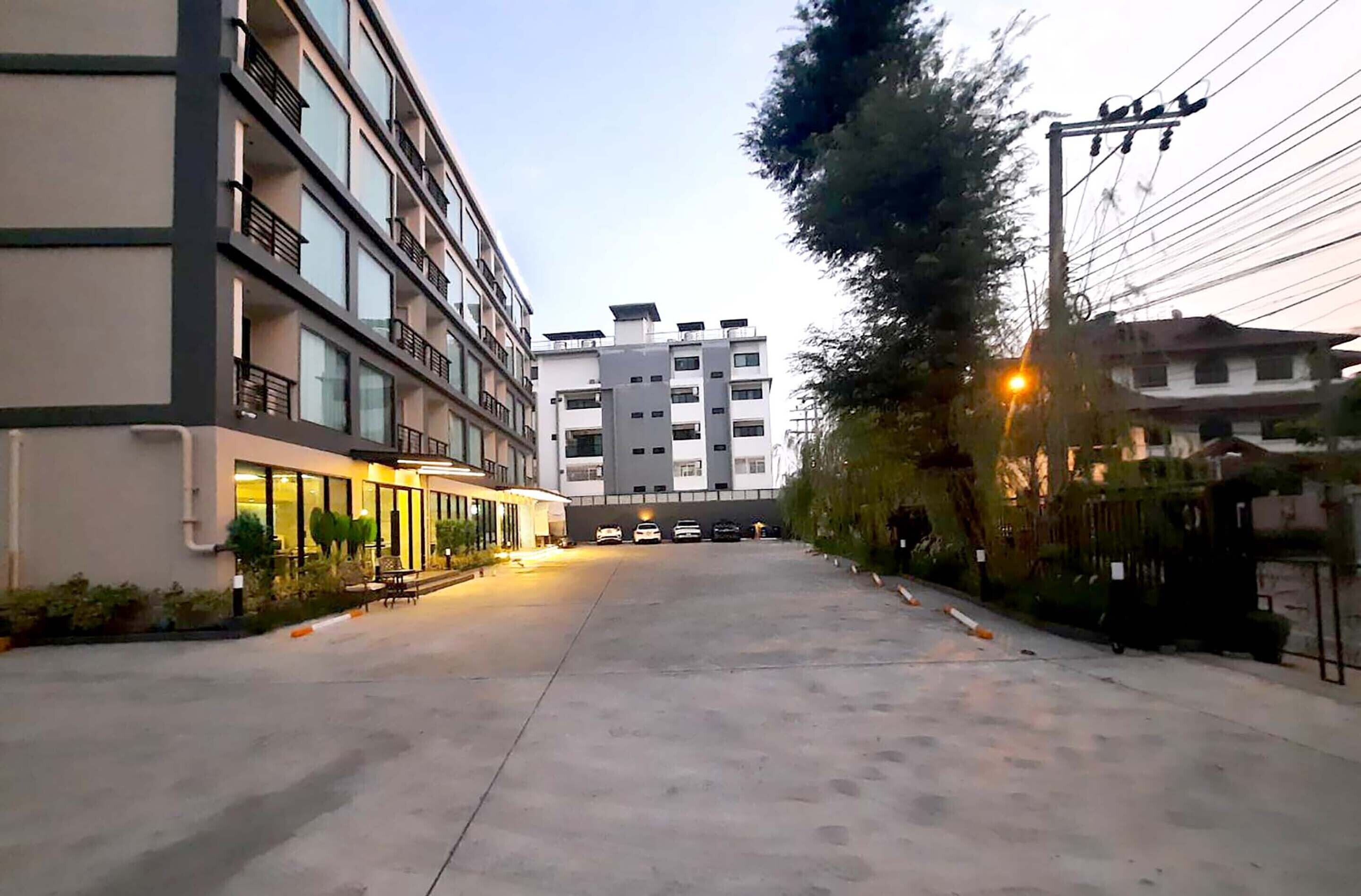 Een meerlaags hotel met een overdekt buitengebied, een parkeerplaats en uitzicht op omliggende gebouwen.