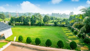 Un jardin bien entretenu, avec une pelouse, des haies taillées avec soin et une variété d’arbres.