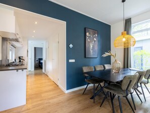 Ein moderner Essbereich mit dunkelblauer Akzentwand, einem Holztisch und einer Pendelleuchte.