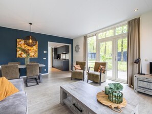 A modern living room with a dining area, a kitchen, and a large window.