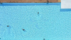 En swimmingpool med klart, blått vatten, en hoppställning och en mur av tegelsten.