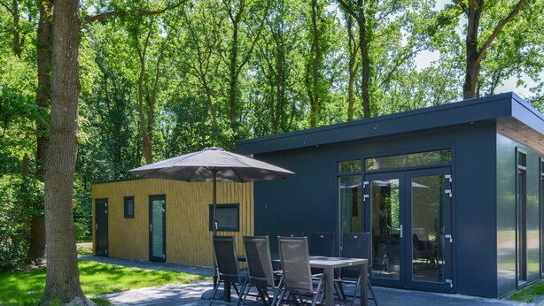 A modern building with a wooden exterior and a glass door entrance. - Beautiful chalet with enclosed garden (Zorgvlied)