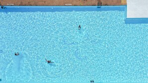 A swimming pool with clear water, a diving board, and a brick wall. - Beautiful chalet with enclosed garden (Zorgvlied)