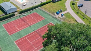 An aerial view of a sports facility with a tennis court, a swimming pool, and surrounding buildings. - Beautiful chalet with enclosed garden (Zorgvlied)