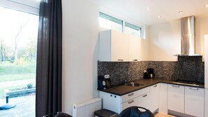 Una cocina moderna con salpicadero de azulejos blancos y negros, electrodomésticos de acero inoxidable y un comedor con mesa y sillas de madera.