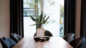 Una mesa de madera con una planta en maceta, un menú enmarcado y dos cuencos.