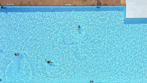 En swimmingpool med klart, blåt vand, et springbræt og en murstensmur.