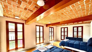 Une chambre avec un plafond en briques, des poutres en bois et de grandes fenêtres.