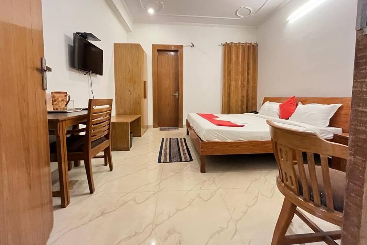 Une chambre à coucher avec un lit, un bureau, une chaise, une télévision et une porte.
