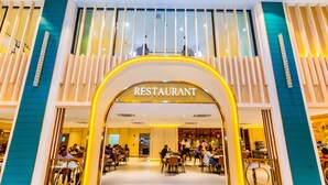 Un ristorante con interni moderni, diverse aree coperte e un ingresso ben visibile.
