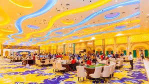 Un'ampia hall d'albergo con diversi tavoli da gioco e un tappeto vivace e decorato.
