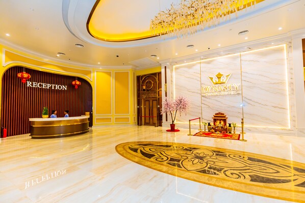 A reception area with a marble floor, a reception desk, and a sign for the Dynasty Casino Hotel.