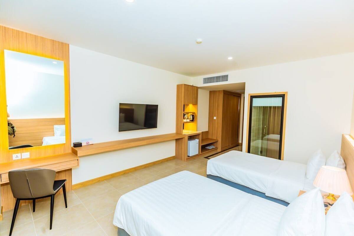 Une chambre d’hôtel avec deux lits, un bureau, une télévision, une armoire et une salle de bain.