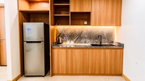 Una cucina compatta con mobili in legno, un frigorifero in acciaio inossidabile, un piano di lavoro in marmo e un lavello.