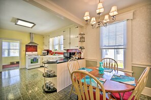 A kitchen with white cabinets, a stove, and a dining area with a table and chairs.