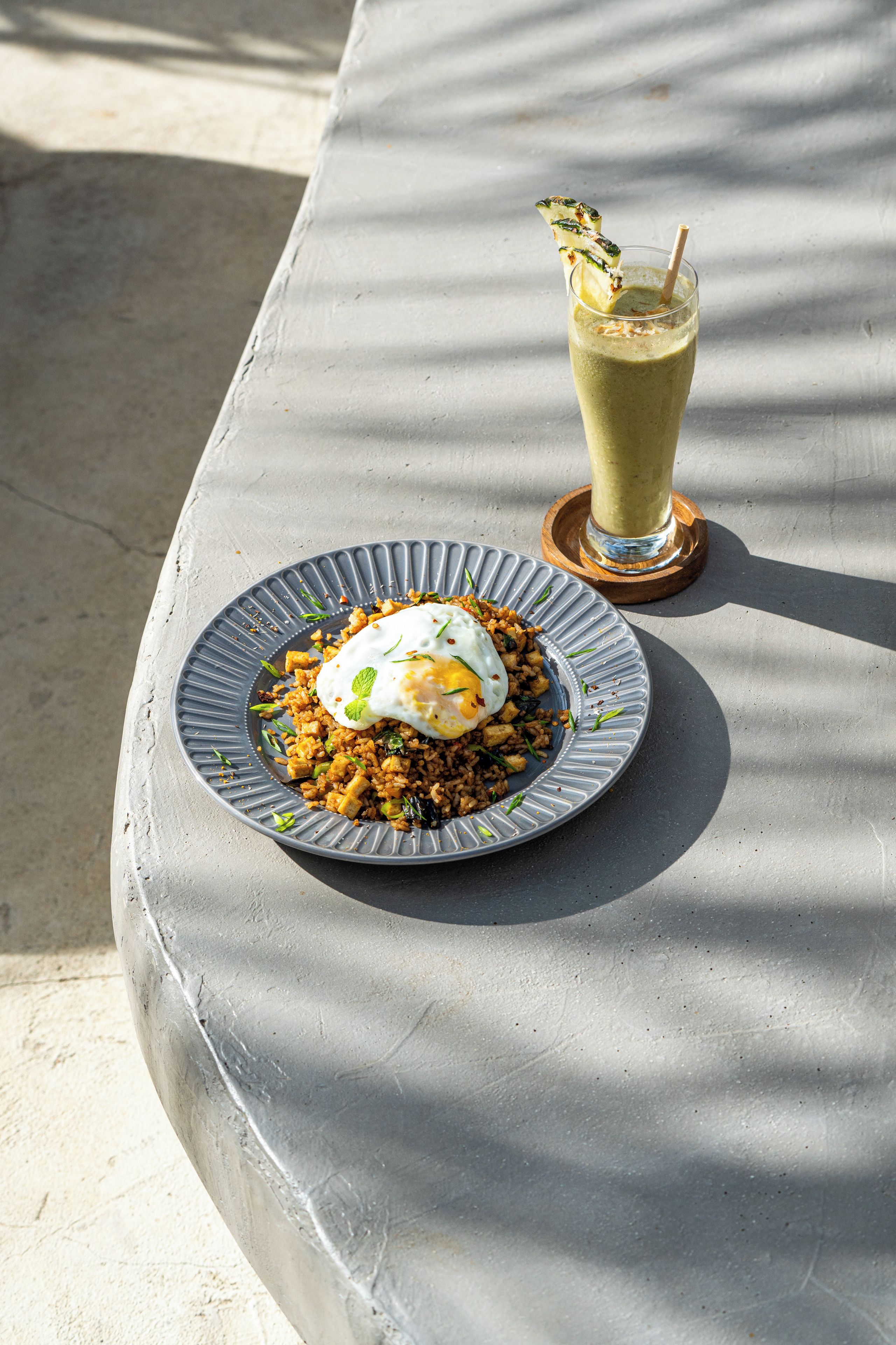A plate of fried rice with a poached egg on a textured gray table.