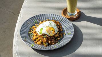A plate of fried rice with a poached egg on a textured gray table.