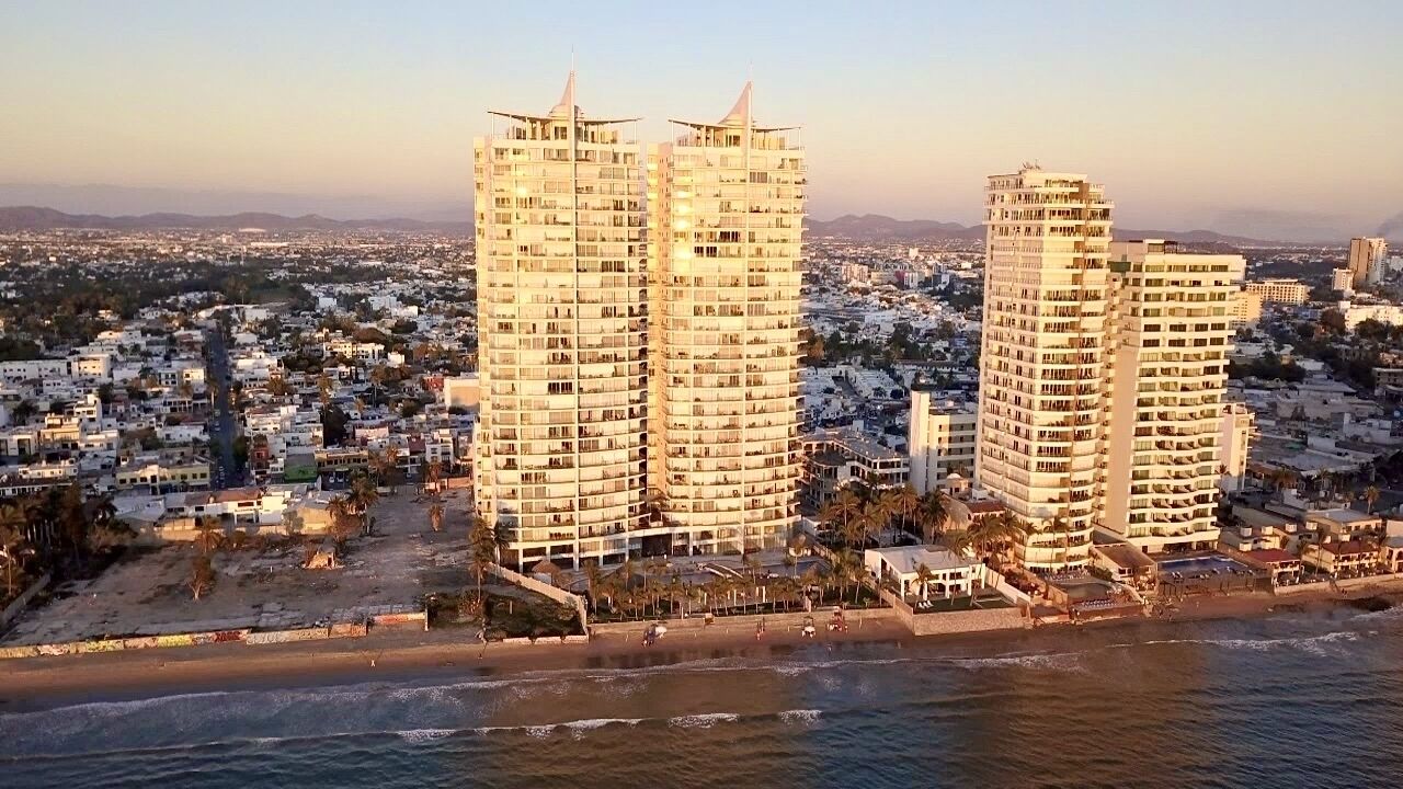 Un paysage urbain côtier avec deux imposants gratte-ciel situés près d’une plage.