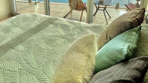 A balcony with a view of the sea and mountains, a bed with patterned bedding, and a chair. - Camino al Mar, Apartment on the Beach with Fabulous Amenities Zona Dorada Pure Luxury (Mazatlán)
