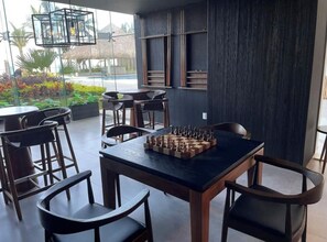 Un espace repas moderne avec un jeu d’échecs posé sur une table, entourée de chaises.