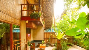 A covered outdoor area with a wooden deck, potted plants, and a seating area.